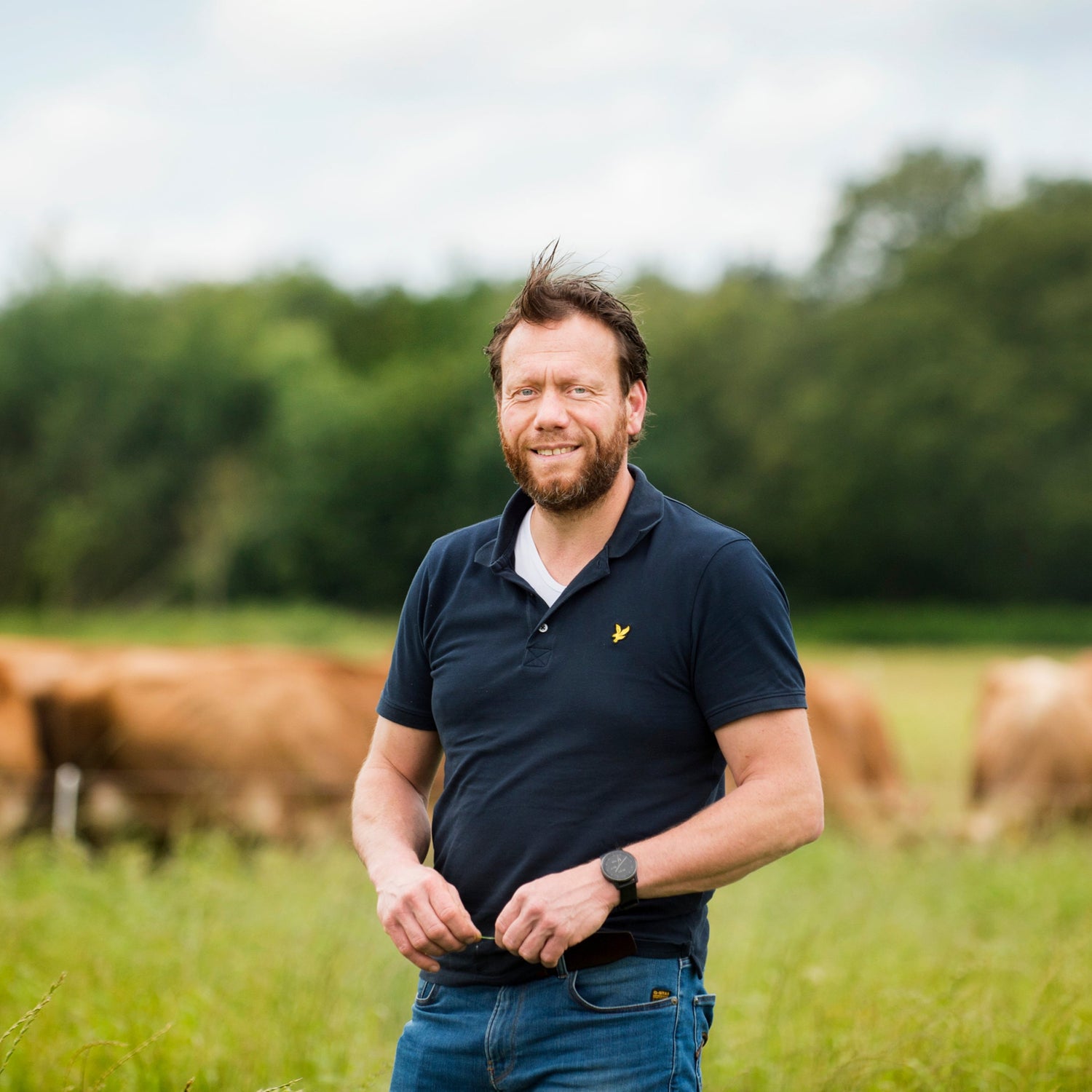 Boer Jakob staat op zijn boerderij met zijn Jersey‑koeien in het kruidenrijk grasveld